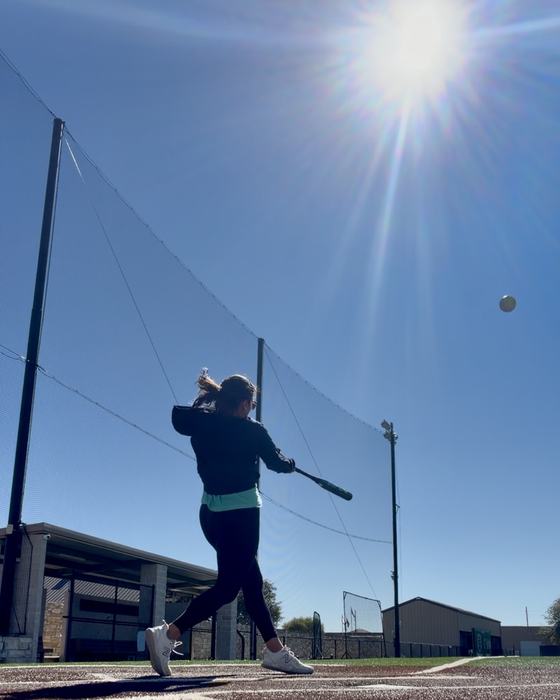 Jamie swinging a bat on a softball field